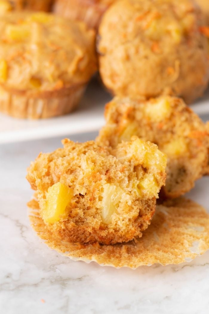 a close up of a carrot pineapple muffin that has been cut down the center to reveal big pieces of pineapple